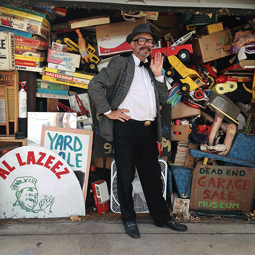 Photo of eclectic man in front of a garage packed with collections. Credit:Sarah Chesnutt, Ang and Mark Leffingwell